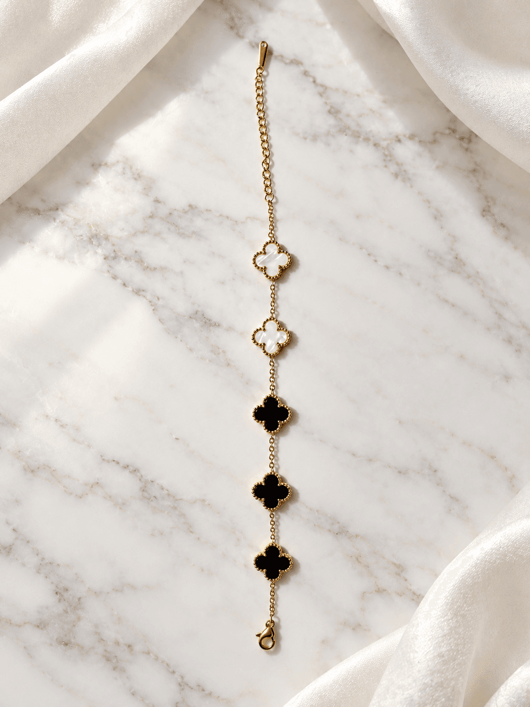 Black and white clover bracelet on marble with ivory shawl