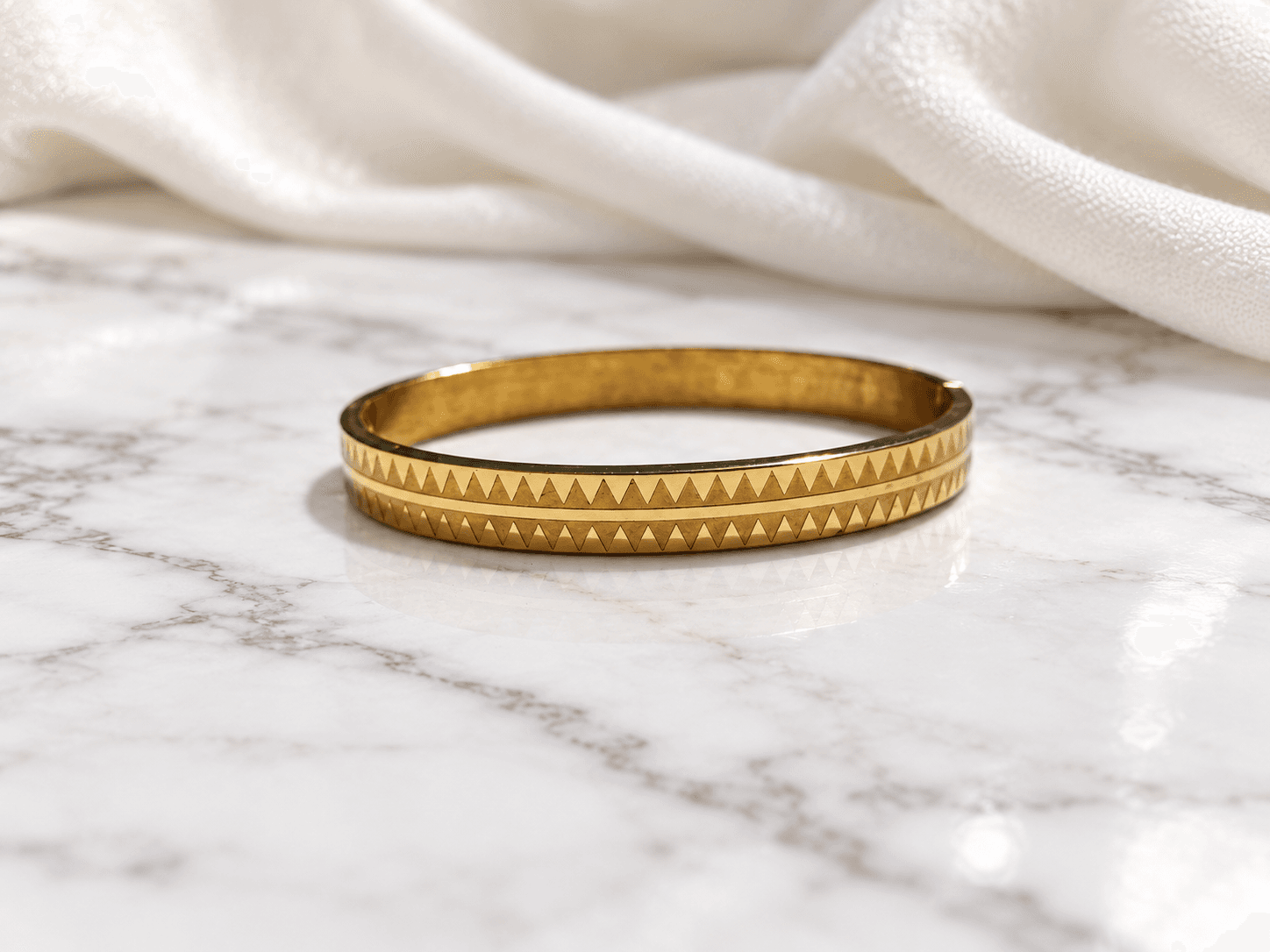 Gold triangle-etched bangle kada on white marble