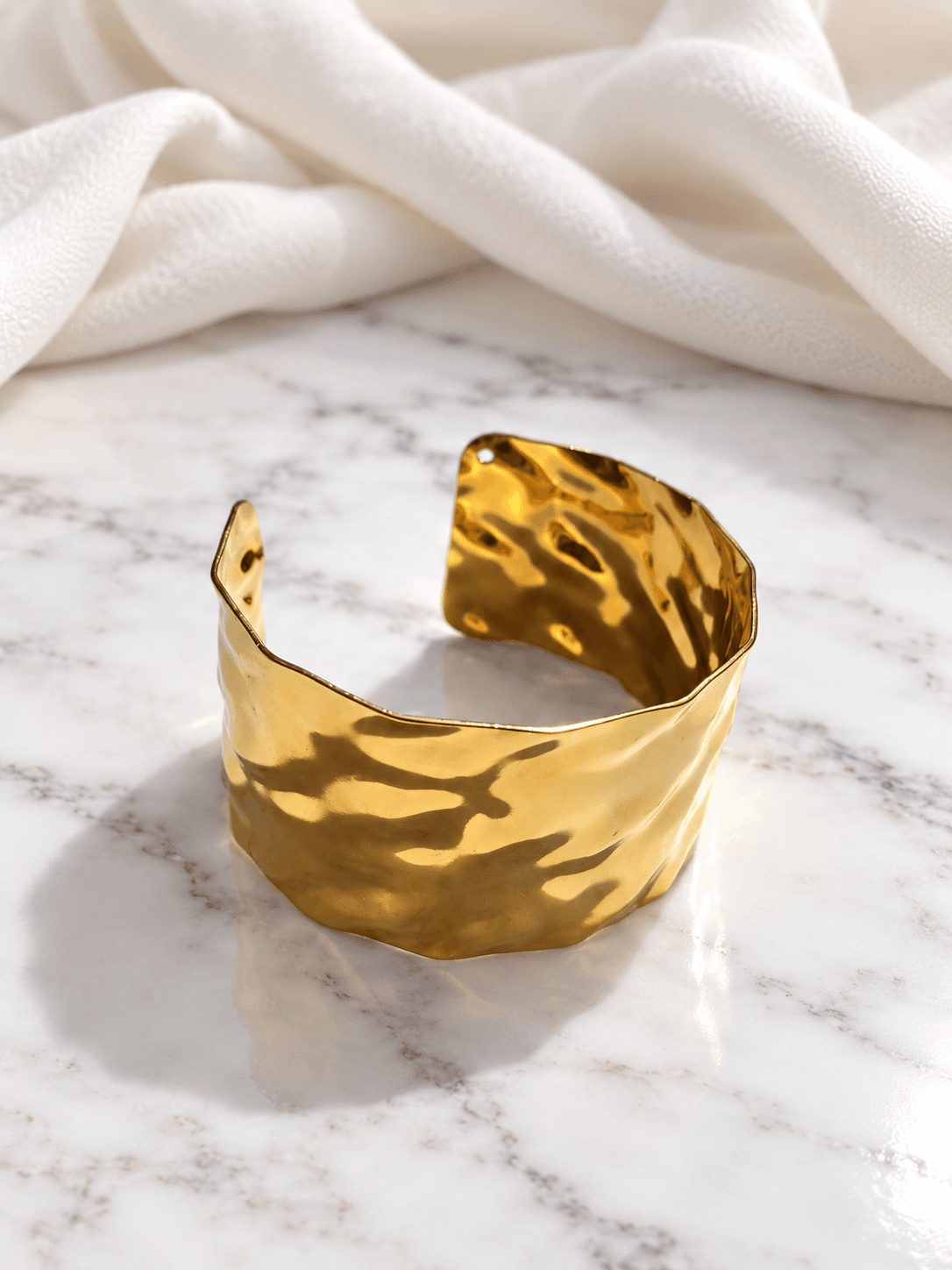 Hammered gold open cuff kada on marble with ivory