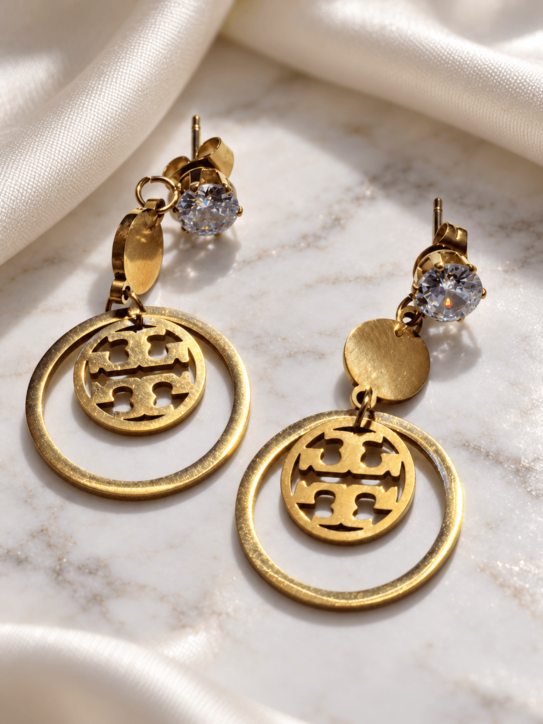Gold monogram circle drop earrings on ivory silk