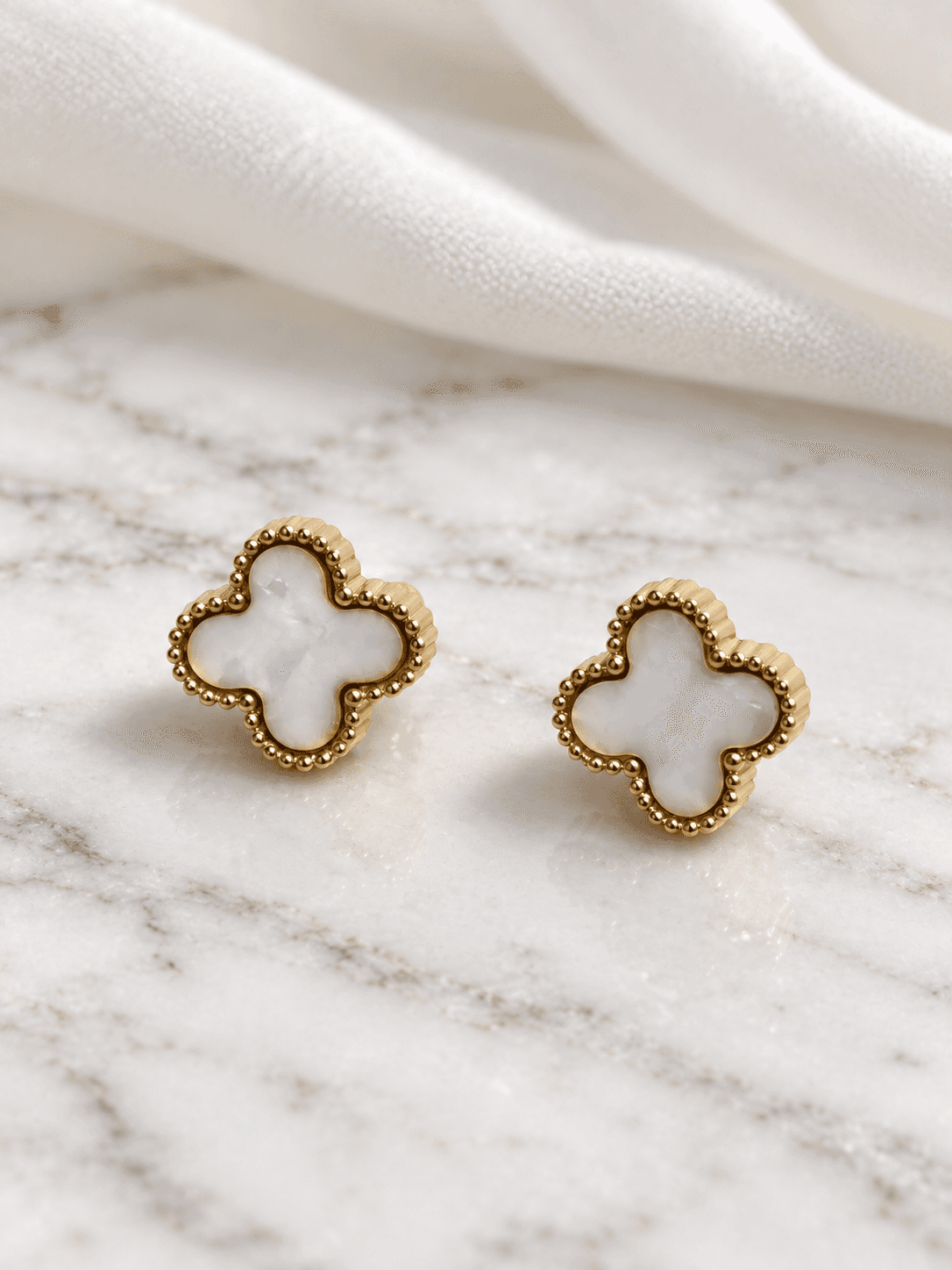 Mother of pearl clover stud earrings on white marble